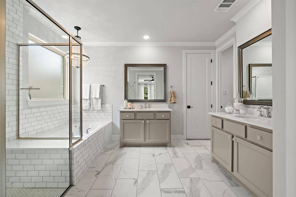Ensuite primary bathroom featuring double vanities and sinks, a walk-in shower, and seperate soaking tub.