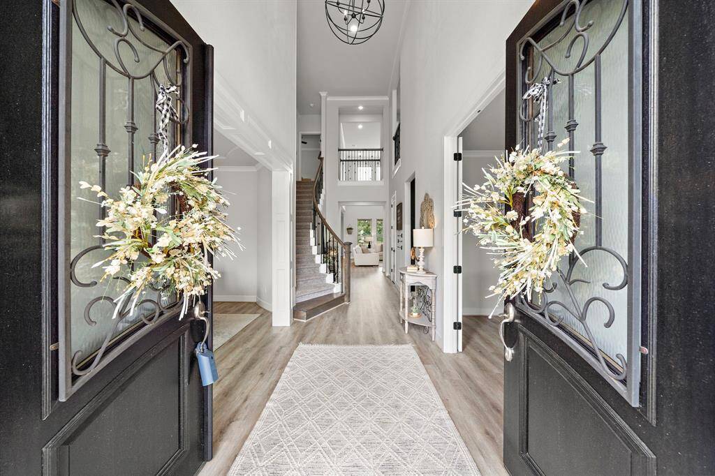Absolutely stunning entryway as you are greeted by double doors, luxury vinyl plank floors, custom lighting, and a curved staircase.