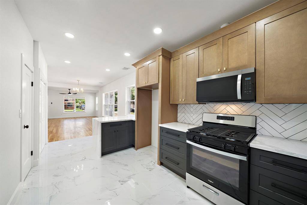 Beautiful waterfall edge on peninsula, marble looking floors, two-toned cabinetry offers a luxuriously feel.