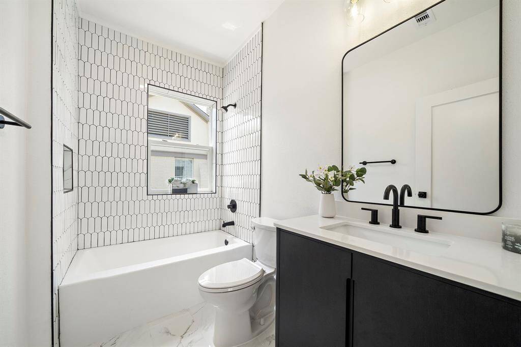 Contemporary bathroom with tub/shower combo, marble like floors and a designer vanity and fixtures.