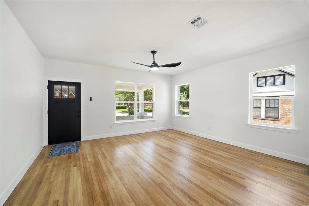 Matte black front door and contemporary ceiling fan add a sleek, modern edge while maintaining a clean and timeless aesthetic.