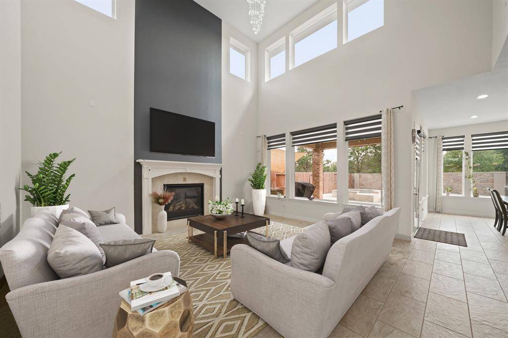 Virtually Staged: Be mesmerized by this open and bright living room! It has a high ceiling, a stunning chandelier, large windows, and a gorgeous fireplace with mantle.