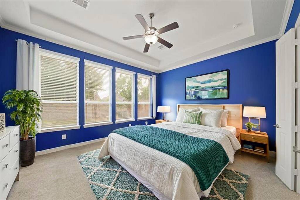 Virtually Staged: Incredible primary bedroom with carpet floors, large windows with privacy blinds, a gorgeous tray ceiling with fan, and an ensuite bathroom.