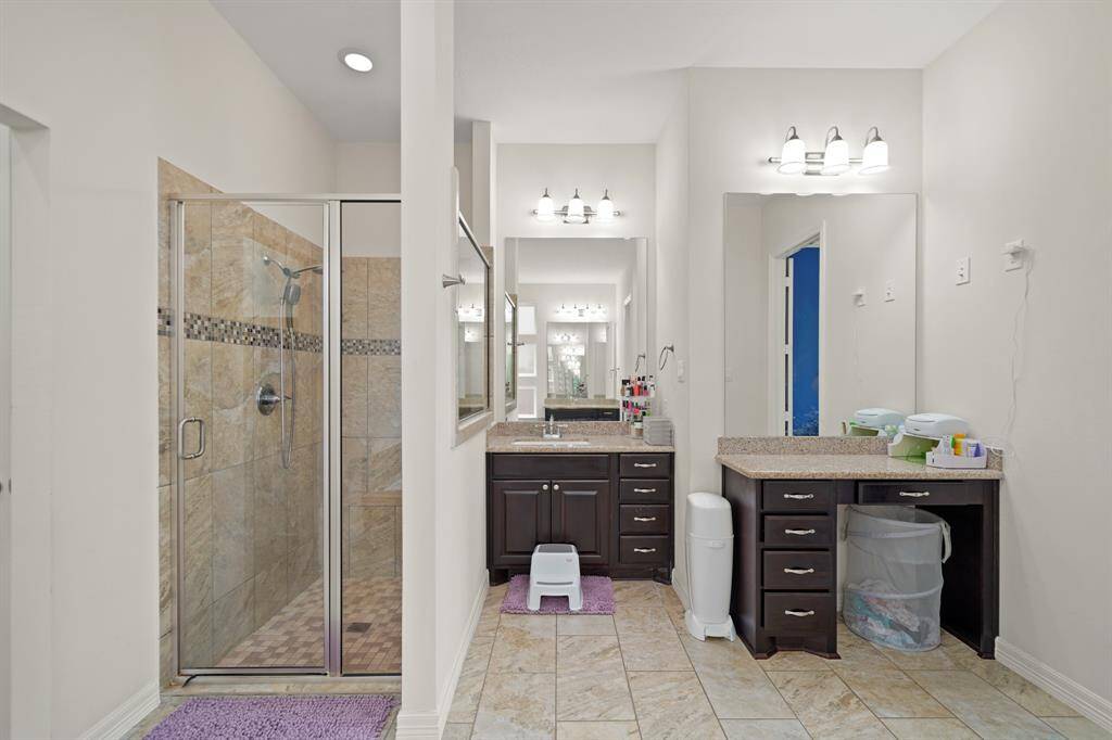 This master bath has tile floors,a vanity area, and a glass enclosed shower.