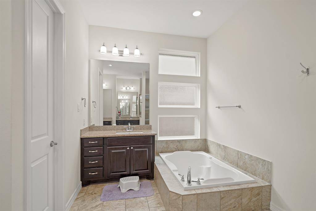 This master bath is complete with dual sinks, granite counters, and a soaking tub with privacy glass.