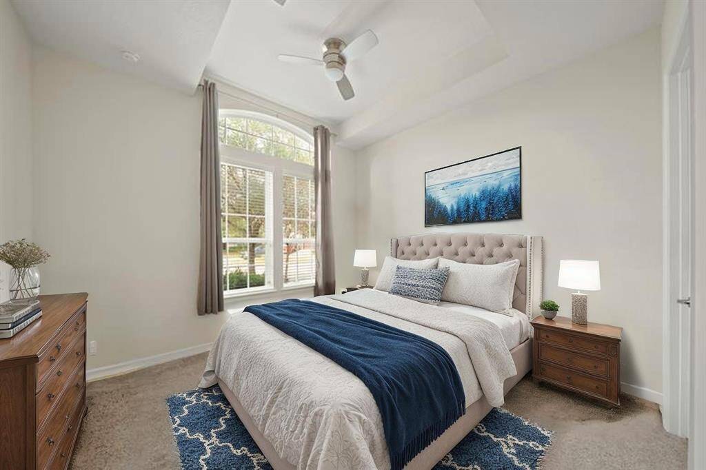 Virtually Staged: This secondary bedroom located at the front of the house has carpet floors, a tray ceiling with a ceiling fan, windows with privacy blinds, and has its own private bathroom.