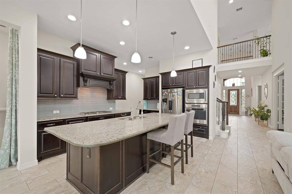 The perfect kitchen does exist! This masterfully equipped kitchen has an oversized island with breakfast bar, recessed and pendant lighting, under cabinet lighting, stainless steel appliances, and plenty of counterspace.