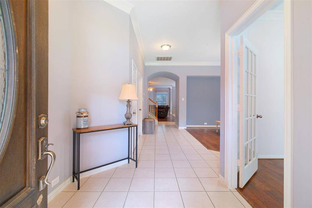 Step inside to a bright and welcoming entryway with elevated ceilings, elegant crown molding, and easy-care tile flooring. A French-doored study sits just off the foyer, setting the tone for the home’s functional and flowing layout.
