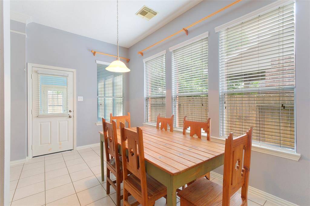 Charming breakfast nook bathed in natural light from a wall of windows, with direct access to the backyard—perfect for casual meals or morning coffee. Easy maintenance tiel flooring and a pendant light complete the space.