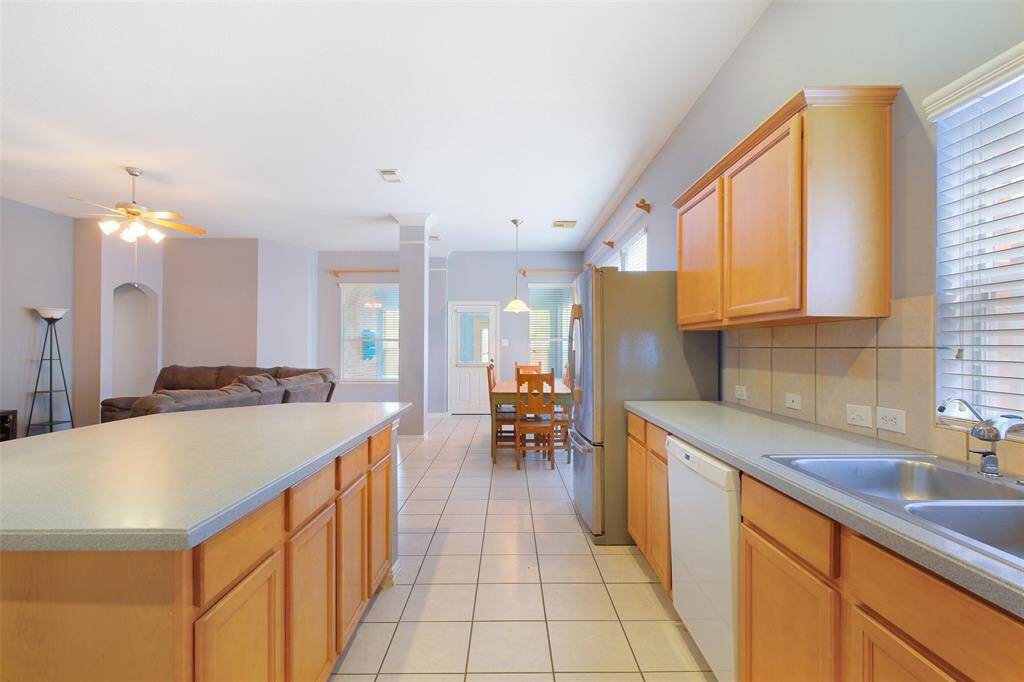 Entertaining is a breeze with this open-concept kitchen with a large center island with seating space, ample cabinetry, and white appliances, all overlooking the breakfast area and family room.