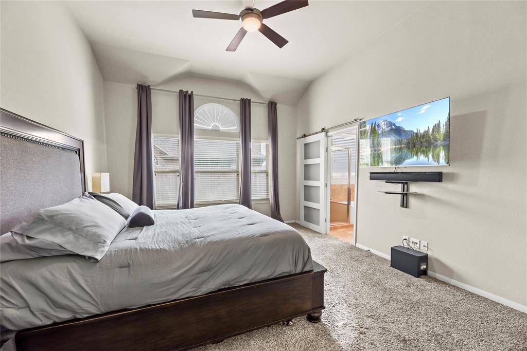 The primary bedroom features a private ensuite bath, discreetly tucked behind charming barn-style glass sliding doors, offering both style and privacy.
