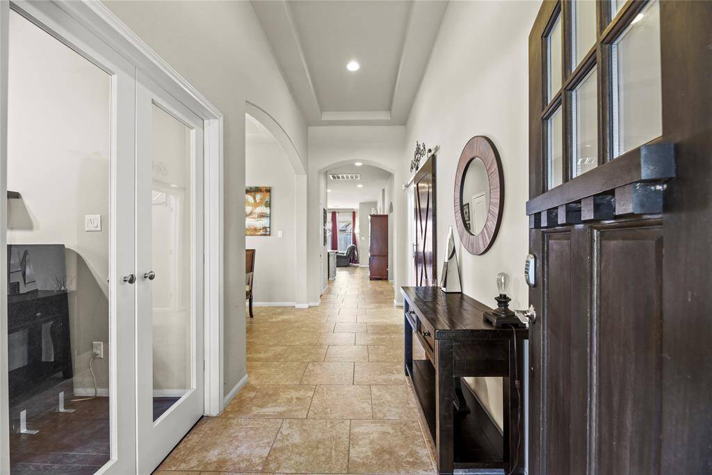 Upon entering the home, you're welcomed by easy-care tile flooring, soaring ceilings, and elegant glass doors to the left that open into a private study