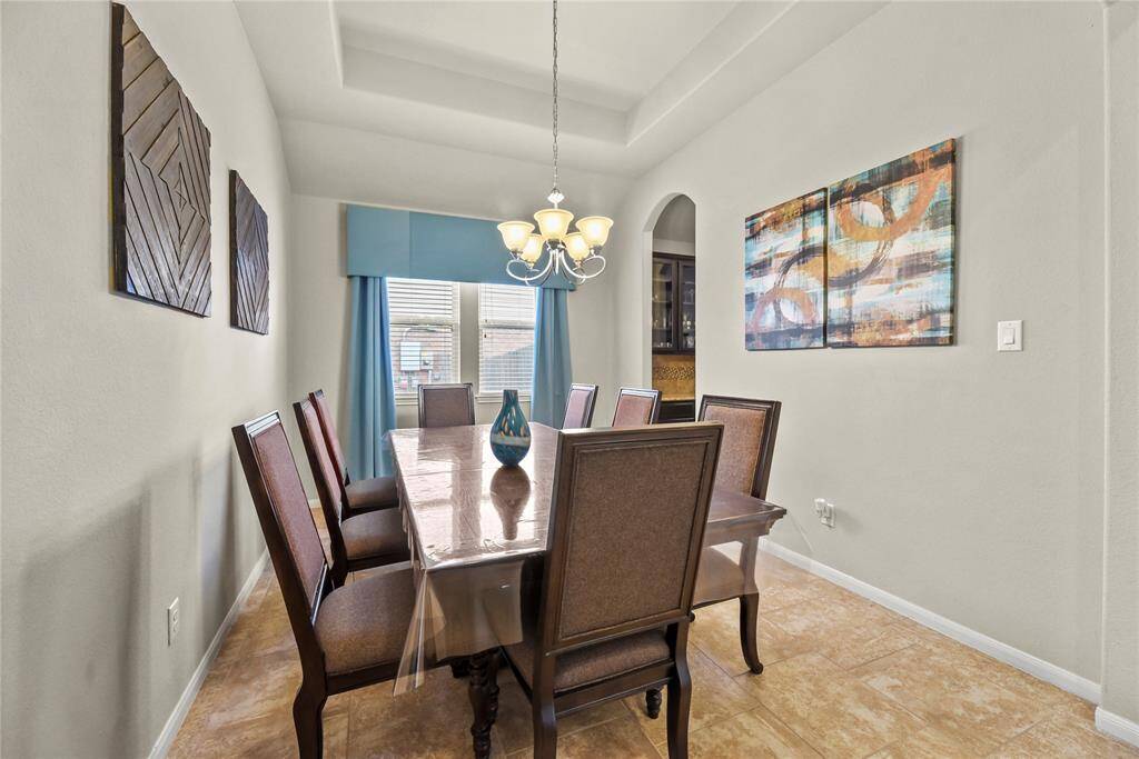 Just beyond the entry, the formal dining room awaits—featuring a coffered ceiling, an elegant chandelier, and abundant natural light, all seamlessly leading to the well-appointed butler’s pantry