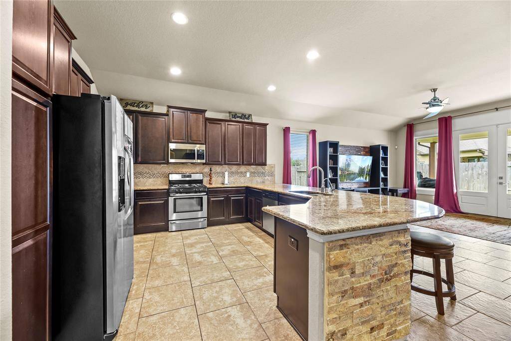 Your chef inspired kitchen awaits! Features include granite countertops paired with a coordinating tiled backsplash, stainless steel appliances, rich cabinets, recessed lighting, and a sprawling island with breakfast bar seating. (Wow, that chef-inspired kitchen sounds like a dream!