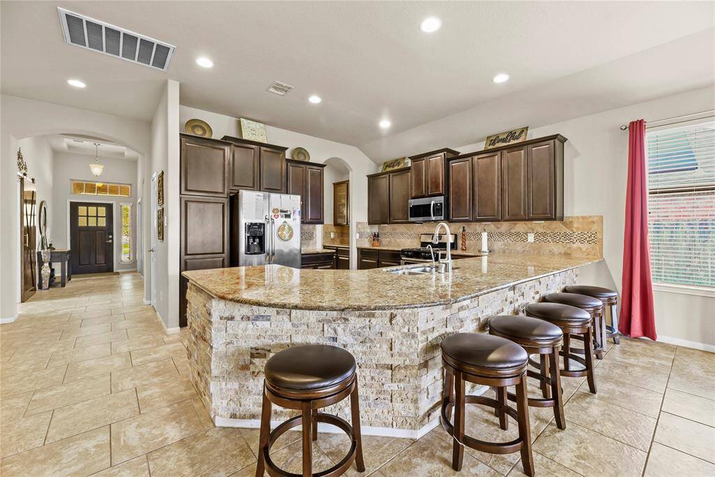 Granite countertops paired with a coordinating stone backsplash not only provide a durable and elegant surface for food preparation but also add a touch of luxury and sophistication to the kitchen.