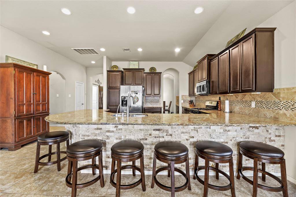 The sprawling island with breakfast bar seating serves as a versatile centerpiece, providing additional workspace, storage, and seating for casual dining or entertaining.
