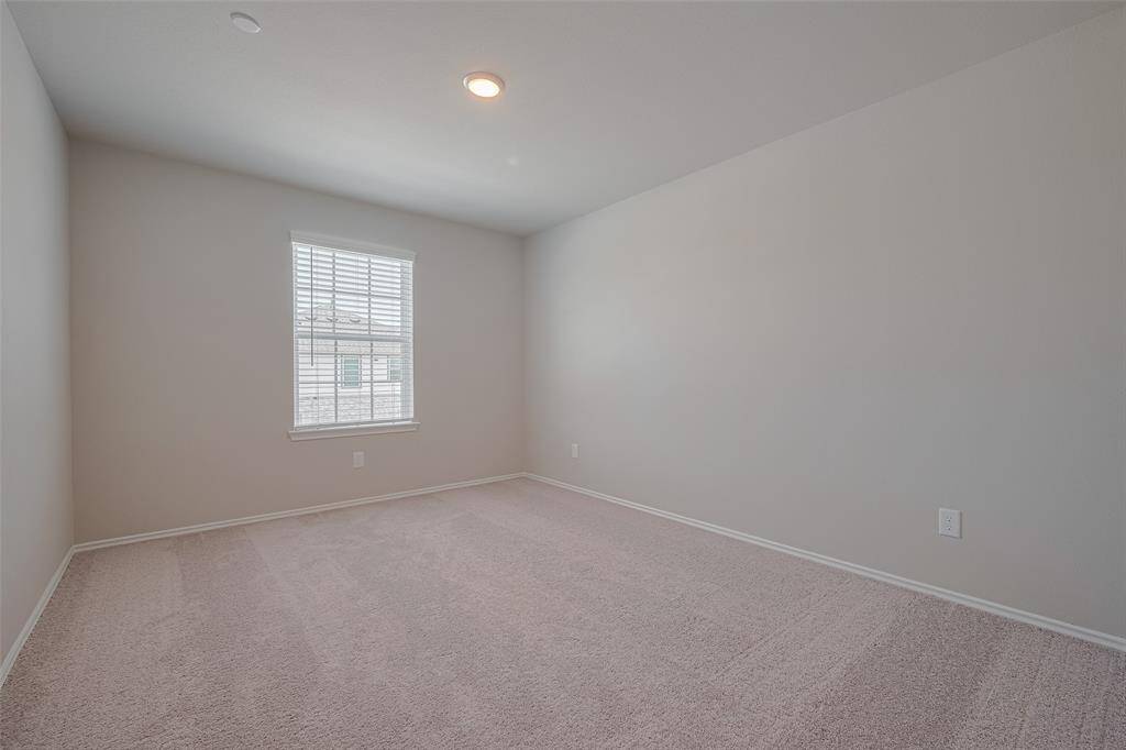 One of two inviting guest rooms, this space features recessed lighting, a large window that fills the room with natural light, plush carpeting, and a generously sized closet.