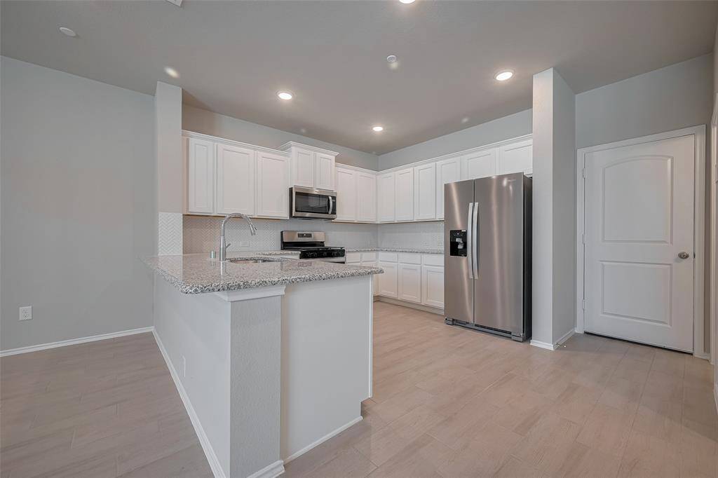 The light and bright kitchen features pristine white cabinets, stainless steel appliances, and a refrigerator that’s included—making it move-in ready and perfect for everyday living or entertaining.