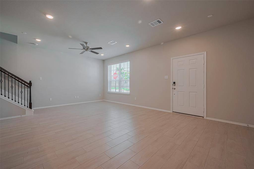 The open and bright living/dining area features tons of recessed lighting, adding warmth and ambiance. Wrought iron spindles lead the way upstairs to the three bedrooms and game room, enhancing the space's elegance and flow.
