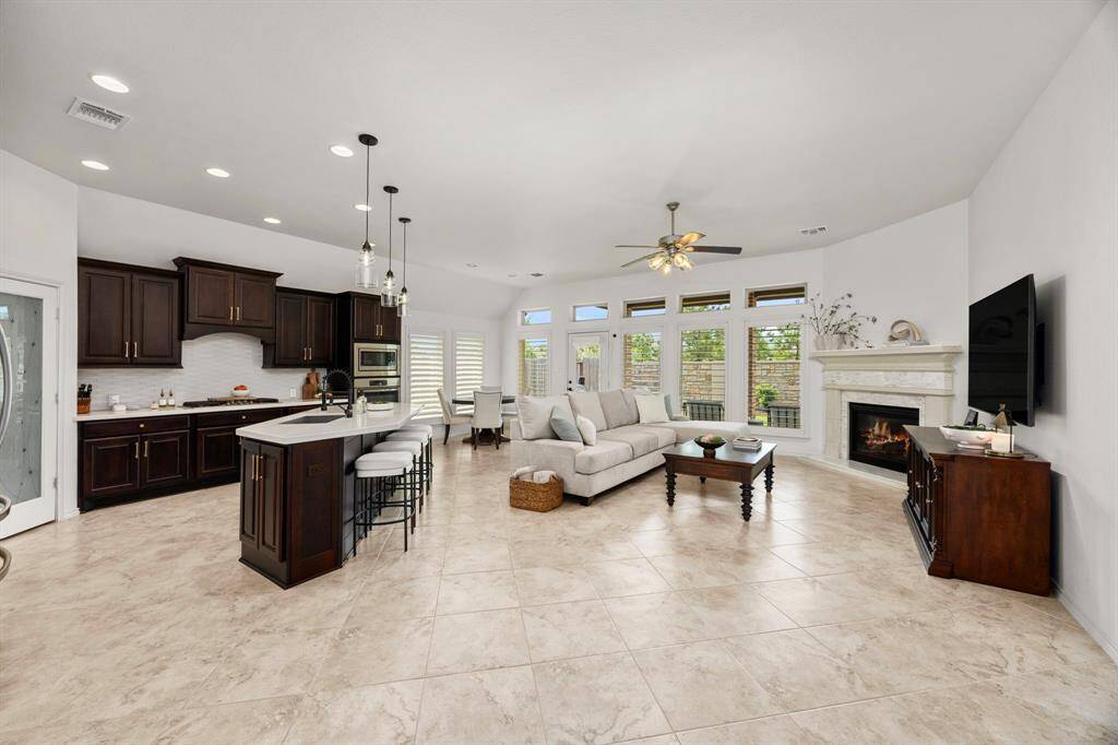 Expansive living space with open kitchen concept to family room and breakfast nook. Large windows with custom plantation shutters, beautiful kitchen cabinetry with gold hardware. Large island with sleek quartz countertops, 5 burner gas cooktop, farmhouse granite sink and modern pendant lighting with beautiful tile flooring throughout.