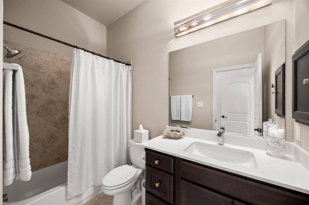 Modern bath with sleek countertops and faucet. Tile floors and tile shower/bath combo.