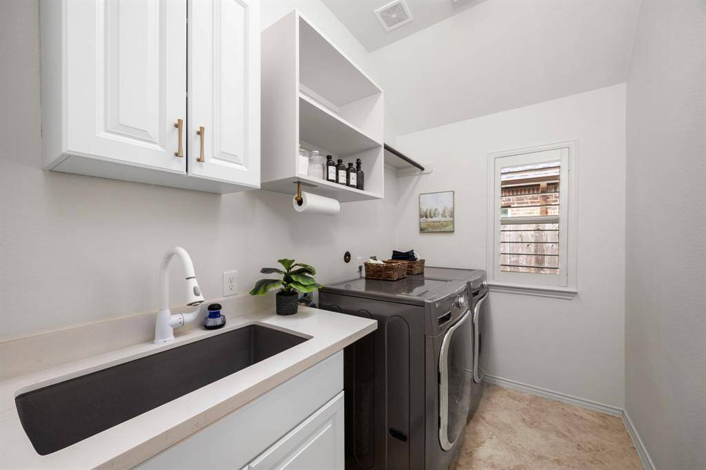 Fully equipped and spacious laundry room with farmhouse granite sink, custom shelves, new cabinetry hardware and custom plantation shutters.