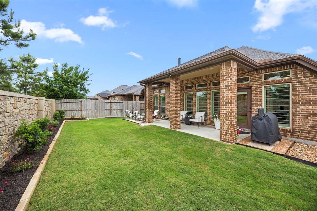 Beautifully maintained backyard with oversized covered patio, custom rock area for grill/barbecue, lush green grass, nice landscaping and beautiful flowerbeds.