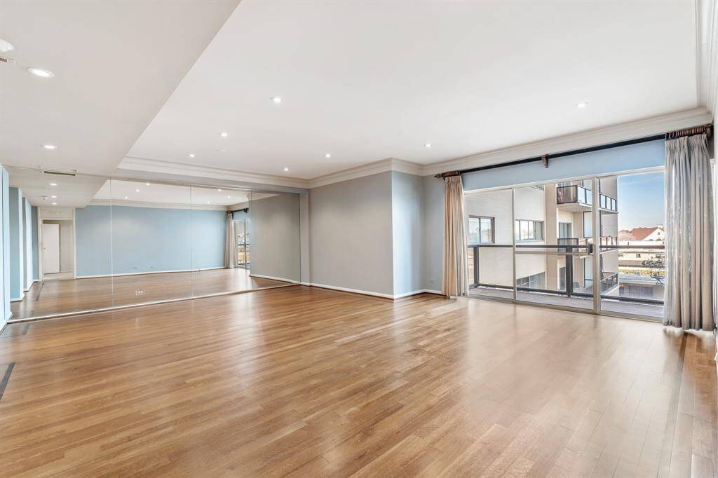 Living and dining with wall of mirrors and balcony access.