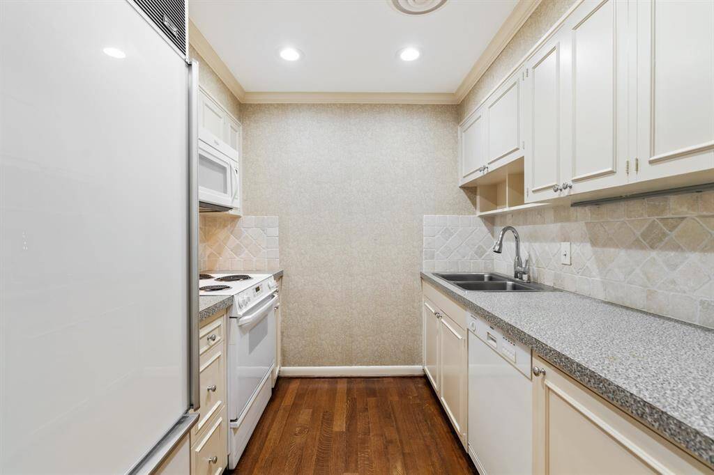 Kitchen with built-in SubZero refrigerator with freezer drawer, hardwood floors, tumbled marble backsplash, recessed lighting, crown molding and neutral tones.