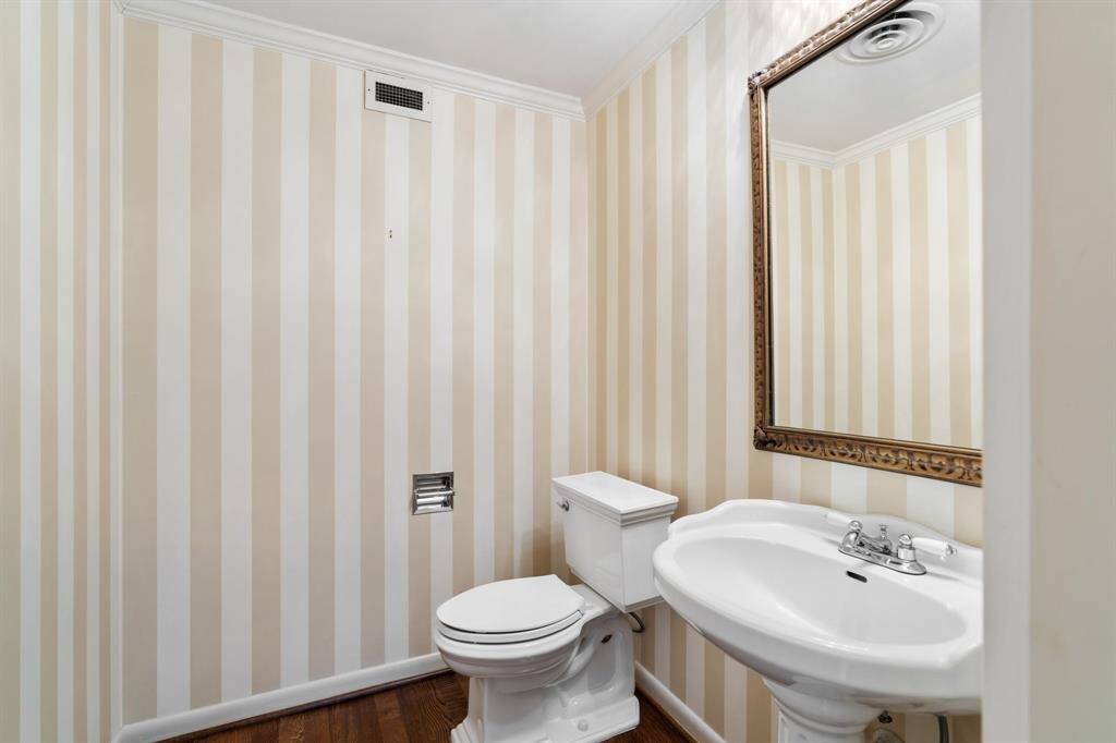 Spacious powder room with hardwoods and designer wall coverings.