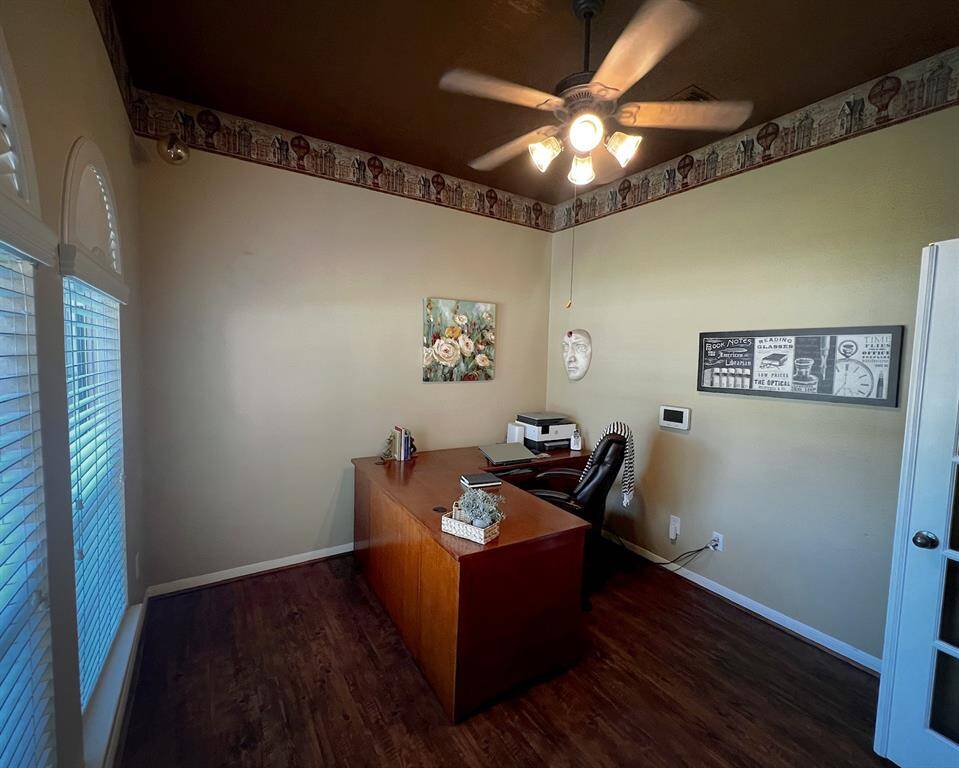 The office/study is equipped with neutral paint, tasteful French doors, and ceiling fan.