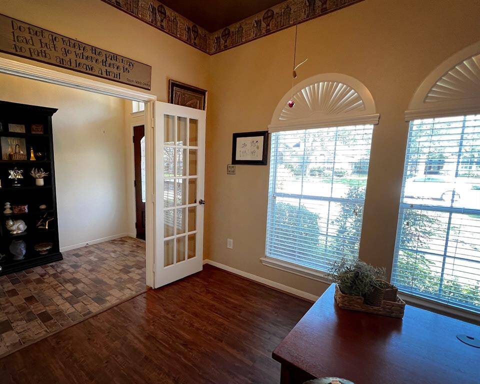 Featuring large arched windows that bring in ample natural light, warm wood flooring, high ceiling, and French doors make this the perfect home office for anyone that works from home.