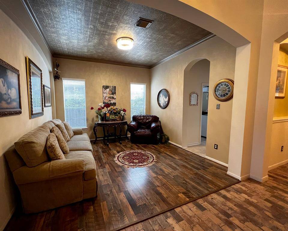 Originally designed as the home's formal dining room, this space has neutral paint, crown molding, a gorgeous textured copper look ceiling, laminate wood flooring and large windows full of natural light. Perfect for the holidays and dinner guests! The decorative archways bring fantastic architectural detail. One leads to a hallway that accesses the spacious laundry room, pantry, and beautiful kitchen.