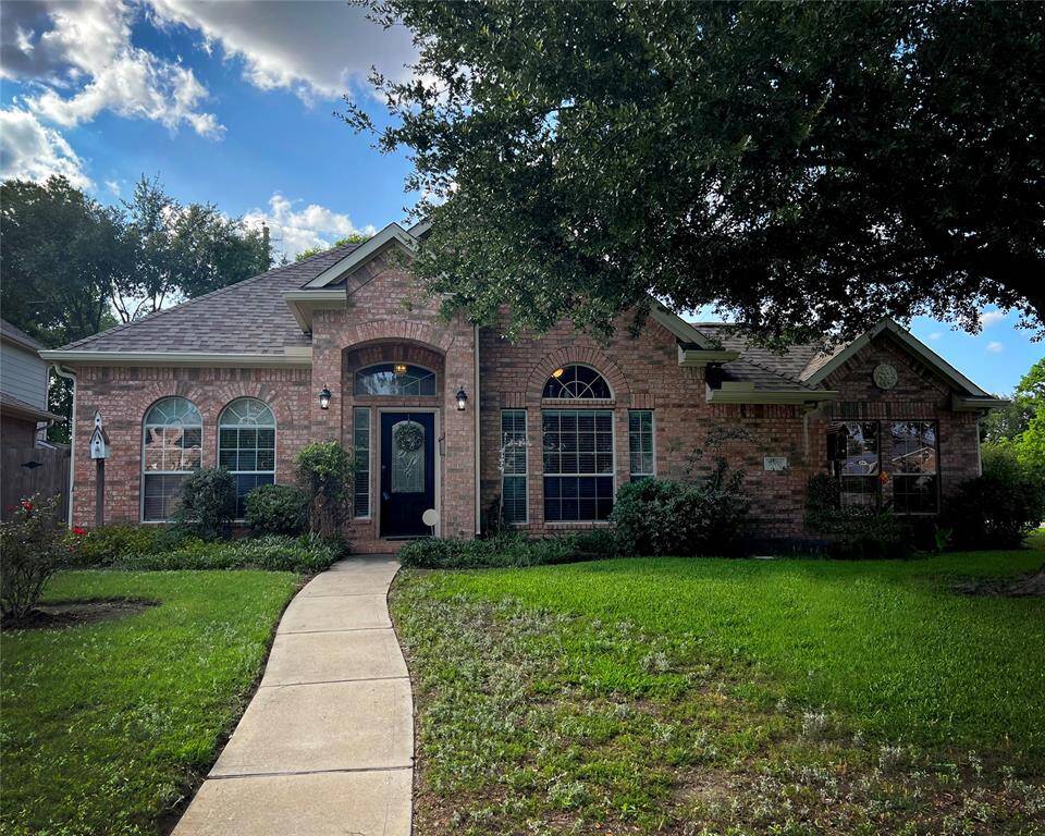 The welcoming front path leads to an arched entryway flanked by elegant exterior lighting.