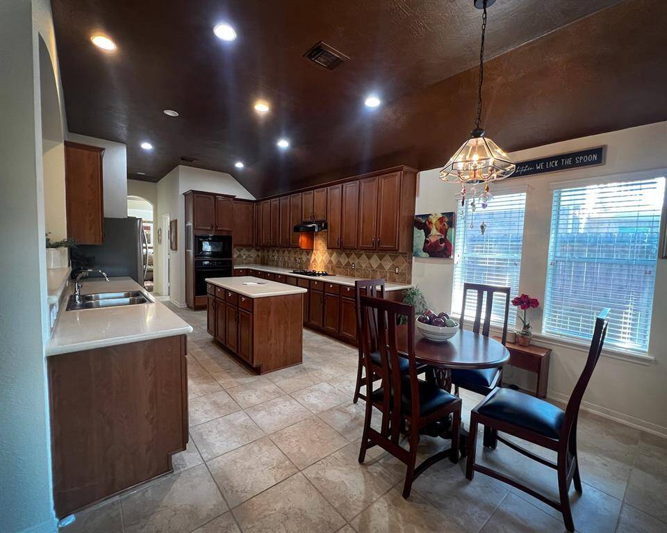 This spacious kitchen features copper accented ceiling, recessed lighting, warm wood cabinetry, a central island, modern appliances and large tile flooring. The adjoining cozy dining area makes daily meals a breeze.