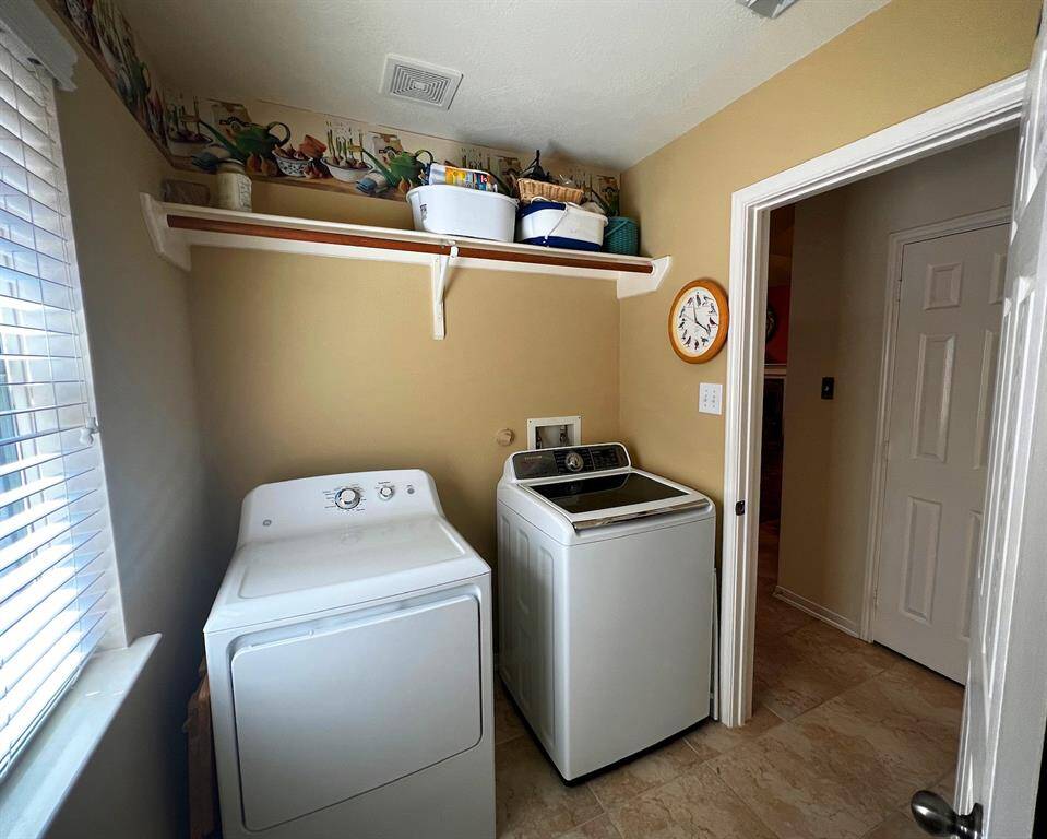 The spacious laundry room offers shelving and hanging space above, and even more natural light through the window.