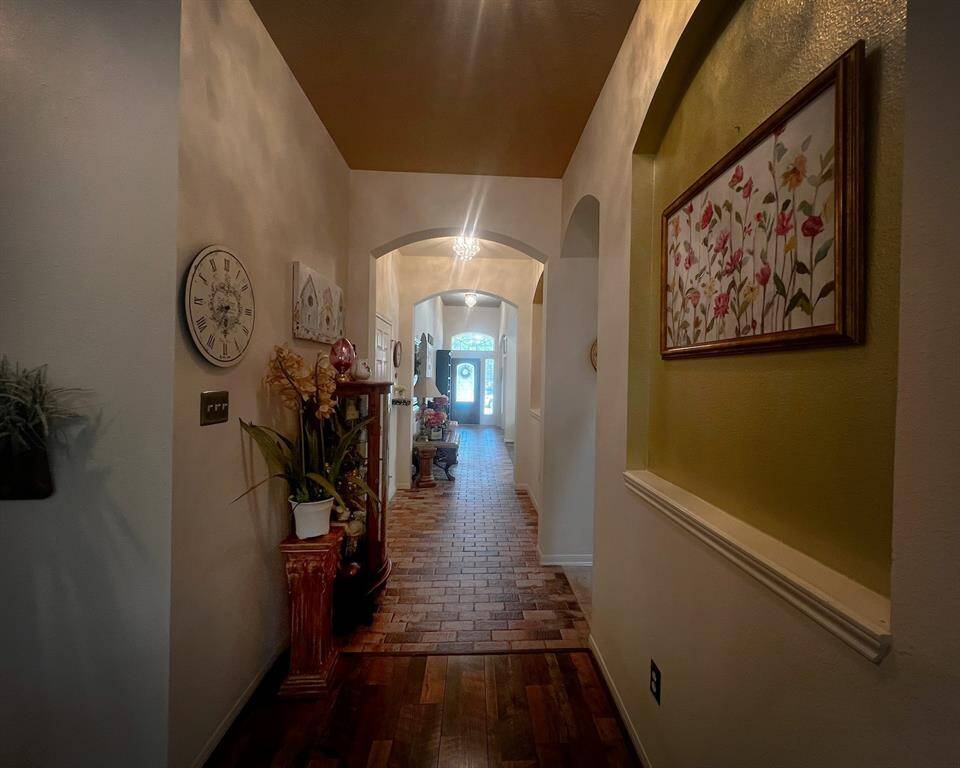 A view from the living room towards the front entrance showcases the elegant arched doorways and art niches that add architectural interest down this wide hallway.