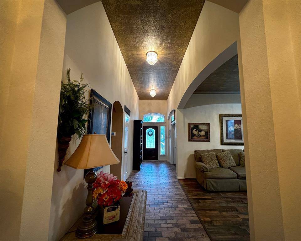 The inviting entry hallway showing off that amazing bricked-tile flooring and copper painted textured ceiling. It opens to the dining room on the right creating a warm, welcoming atmosphere.