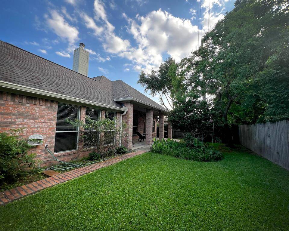 This excellent backyard, features lush green grass, mature vegetation, flower beds surrounded by a gorgeous brick pathway, as well as a cozy covered patio for your outdoor relaxation.