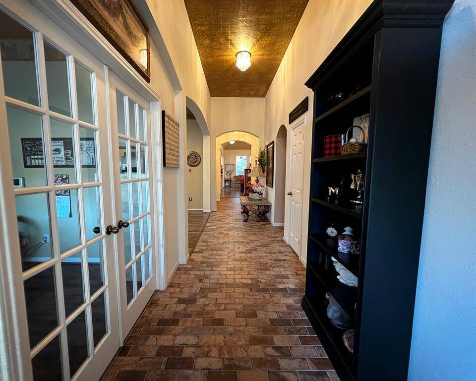 The front entrance showcases amazing brick flooring and a complimentary warm, golden copper painted ceiling. The elegant French doors on the left lead to the private study.