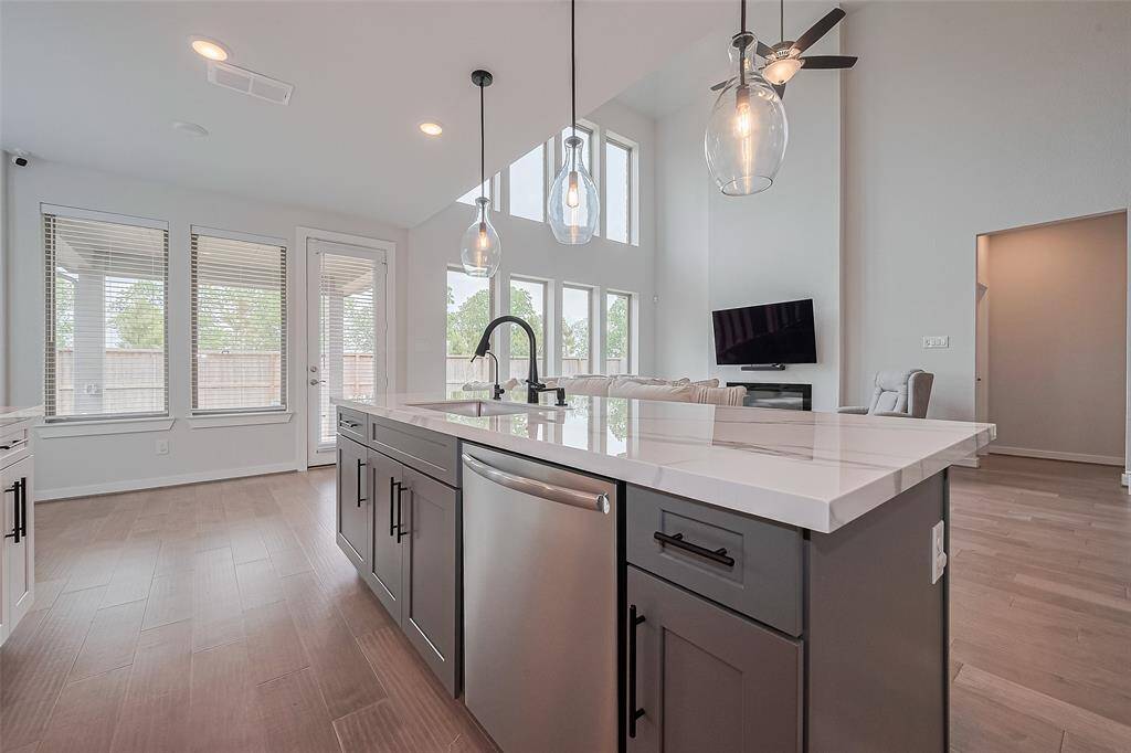 The open layout flows into a bright living area with large windows and high ceilings, creating an inviting and airy atmosphere.