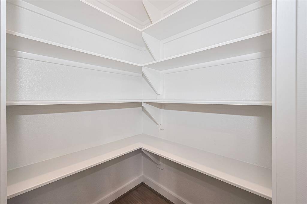Spacious walk-in pantry with multiple white shelves, providing ample storage space.