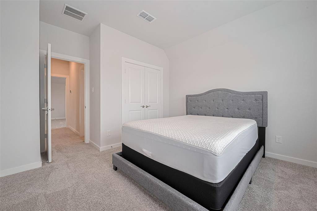 Features a double closet and a gray upholstered bed. The space is clean and minimalistic with a neutral color palette, ideal for personalizing.