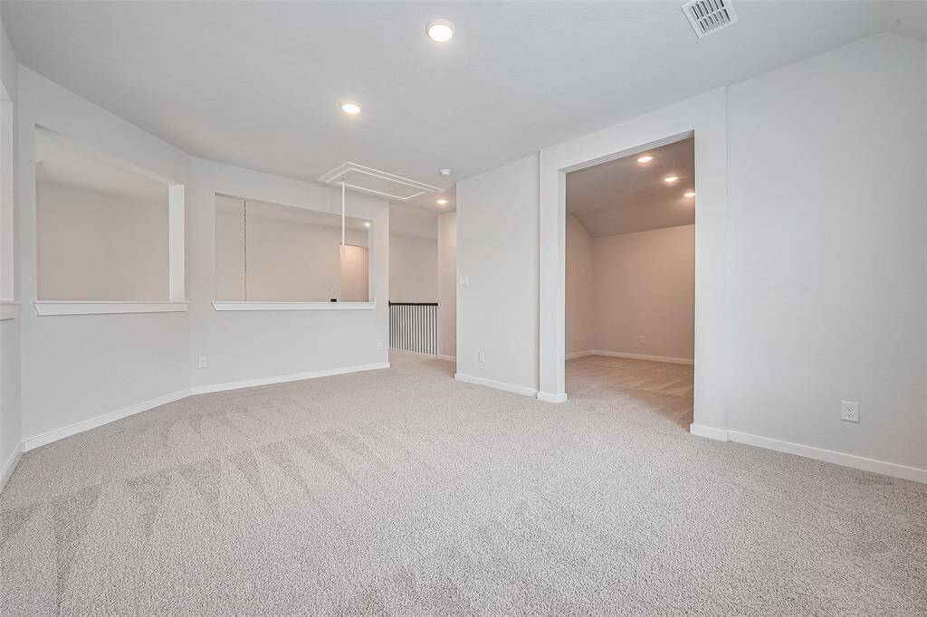 This spacious game room features soft carpeting, neutral walls, recessed lighting, for a modern, airy feel. Ideal for family fun and entertainment, play, or a casual lounge area or a teen hangout space.