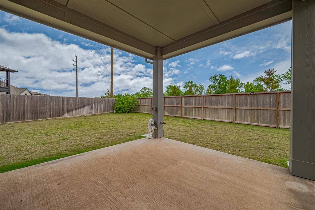 Spacious backyard with a covered patio, privacy fence, and a well-maintained lawn. Perfect for outdoor activities and relaxation.