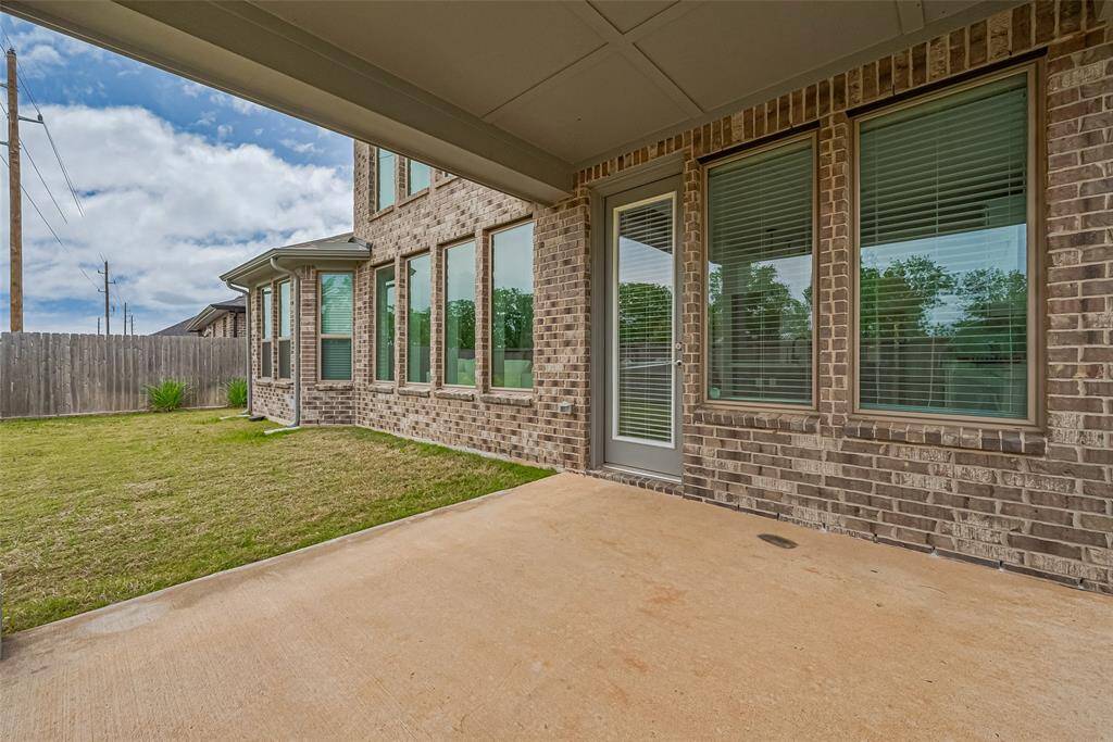 This photo showcases a covered patio area with concrete floor. The patio overlooks a fenced backyard offering a private outdoor space.
