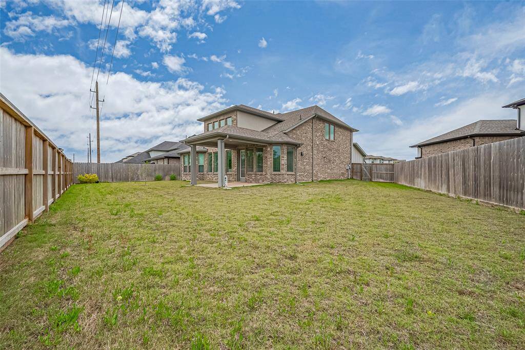 Spacious backyard with a well-maintained lawn, enclosed by a wooden fence.
