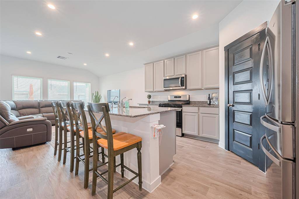 Open-concept living area and kitchen illuminated by soft recessed lighting, creating a warm and inviting atmosphere throughout the heart of the home.