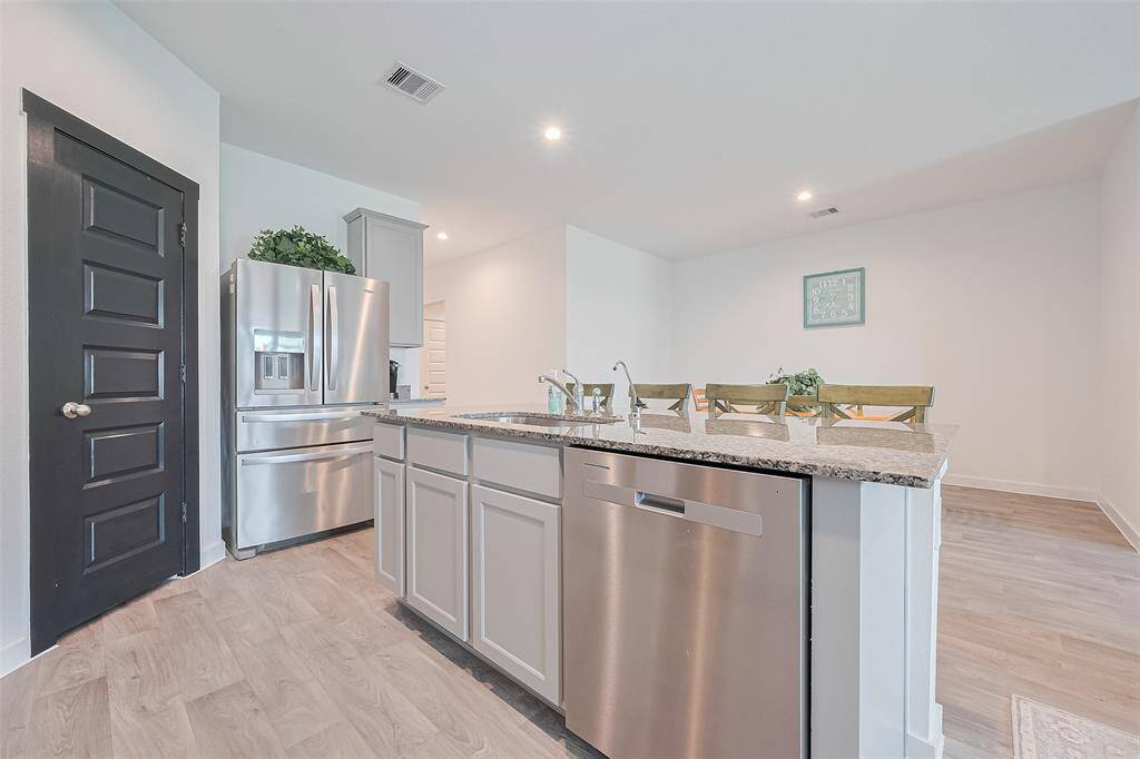 The central island doubles as a practical workspace with a built-in sink and casual seating, perfect for daily living and hosting.