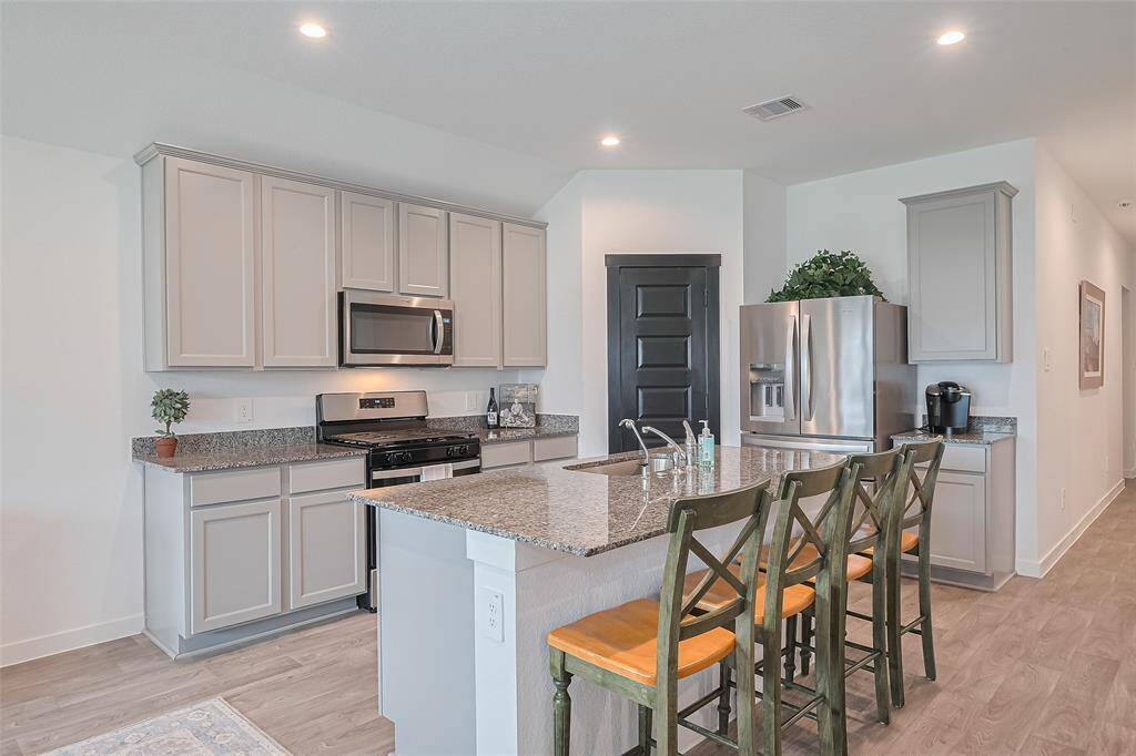 The island with bar seating subtly defines the kitchen as its own zone while maintaining the home’s fluid layout.